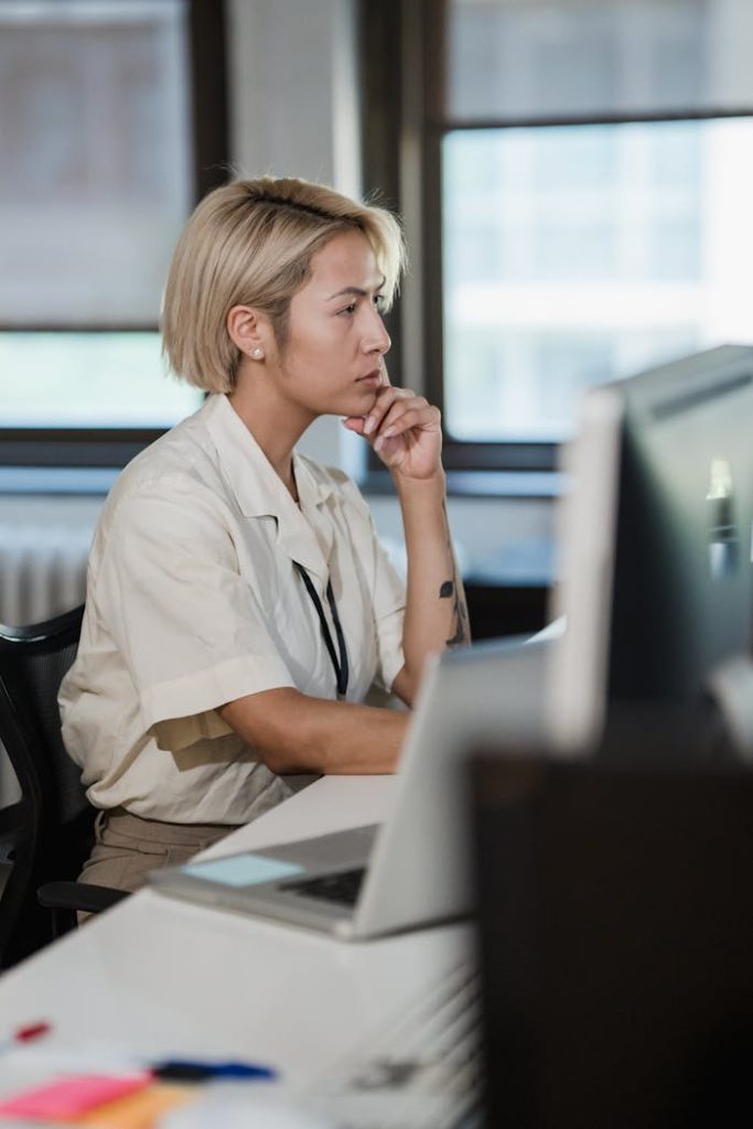 Woman deeply focused on work at her desk in a modern office setting.